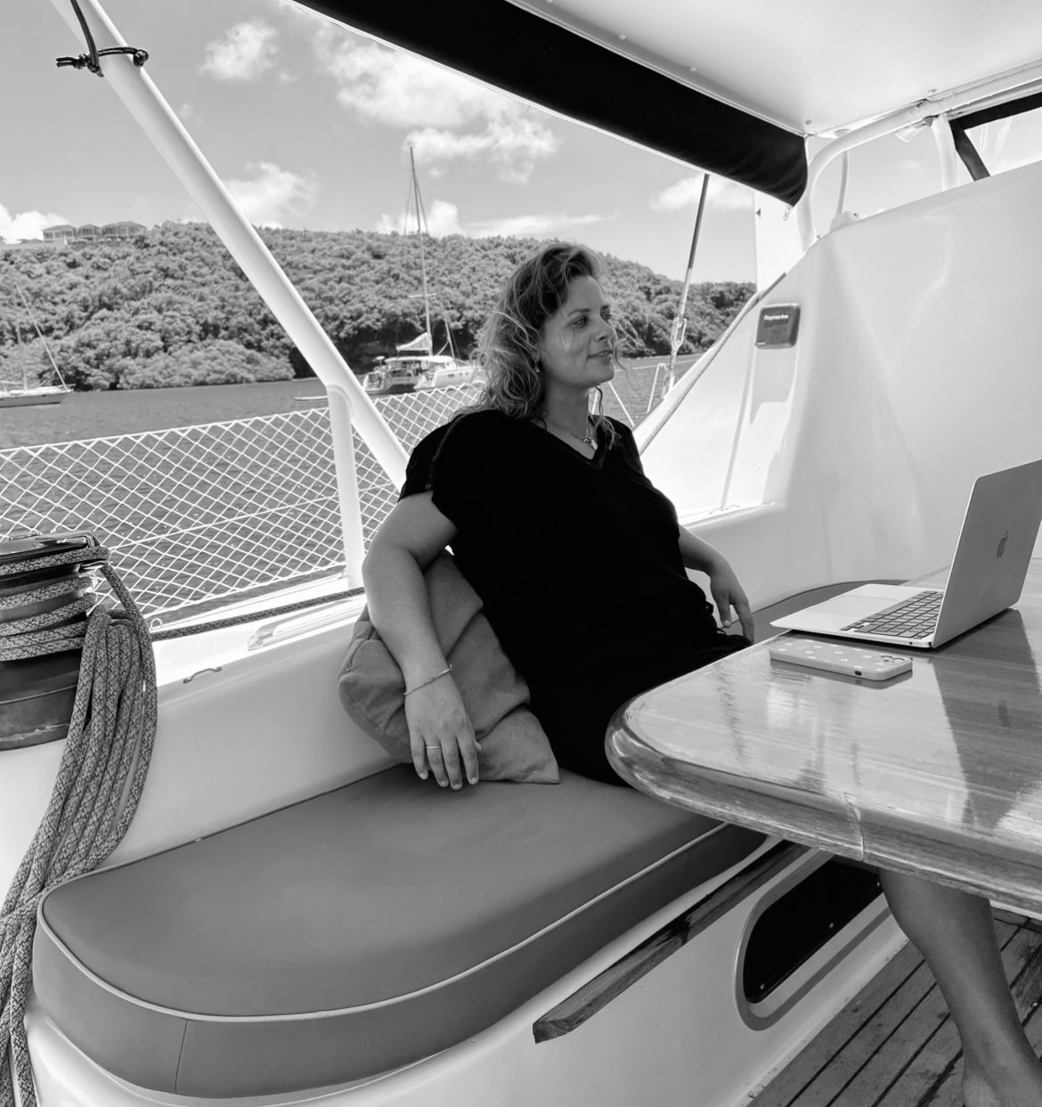 Een vrouw zit op een boot met een laptop op tafel
