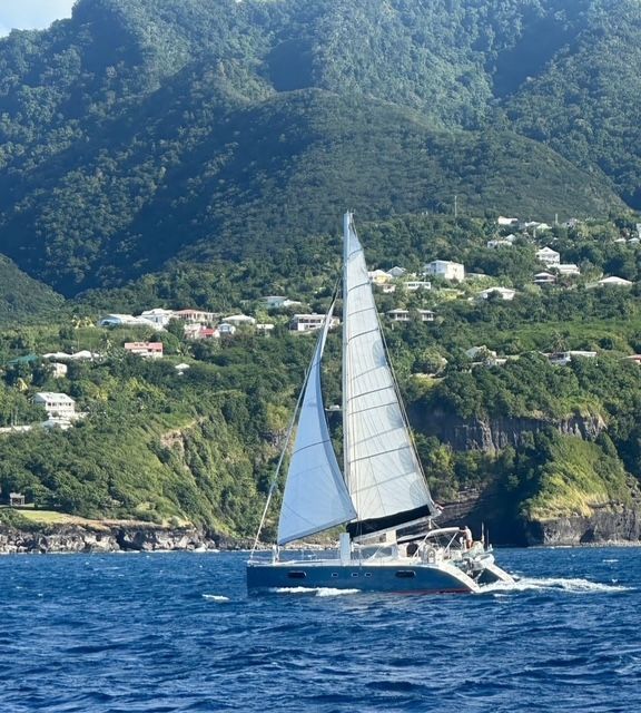Een zeilboot in de oceaan met bergen op de achtergrond