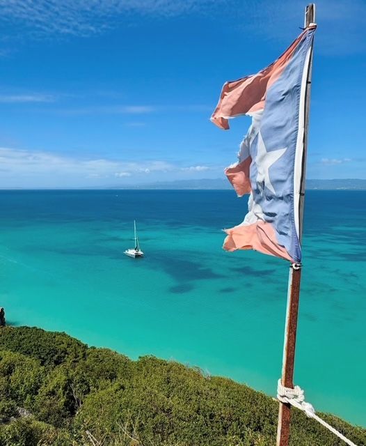 Een vlag op een stok met uitzicht op de oceaan met een boot in de verte
