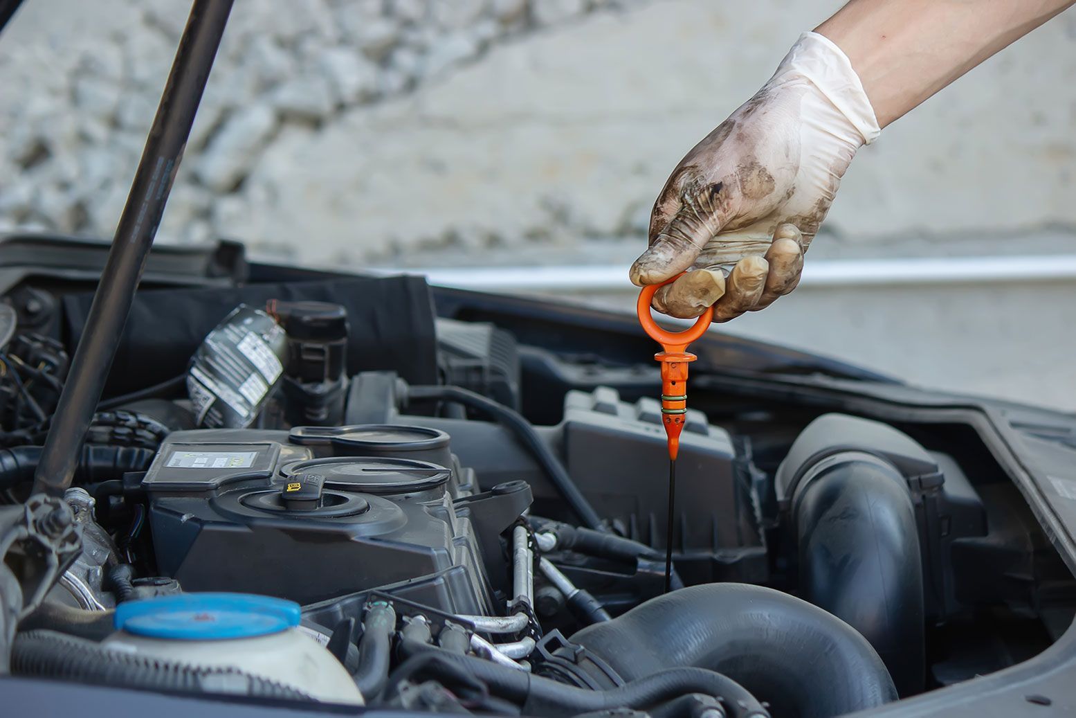 Person checking engine oil level in car.