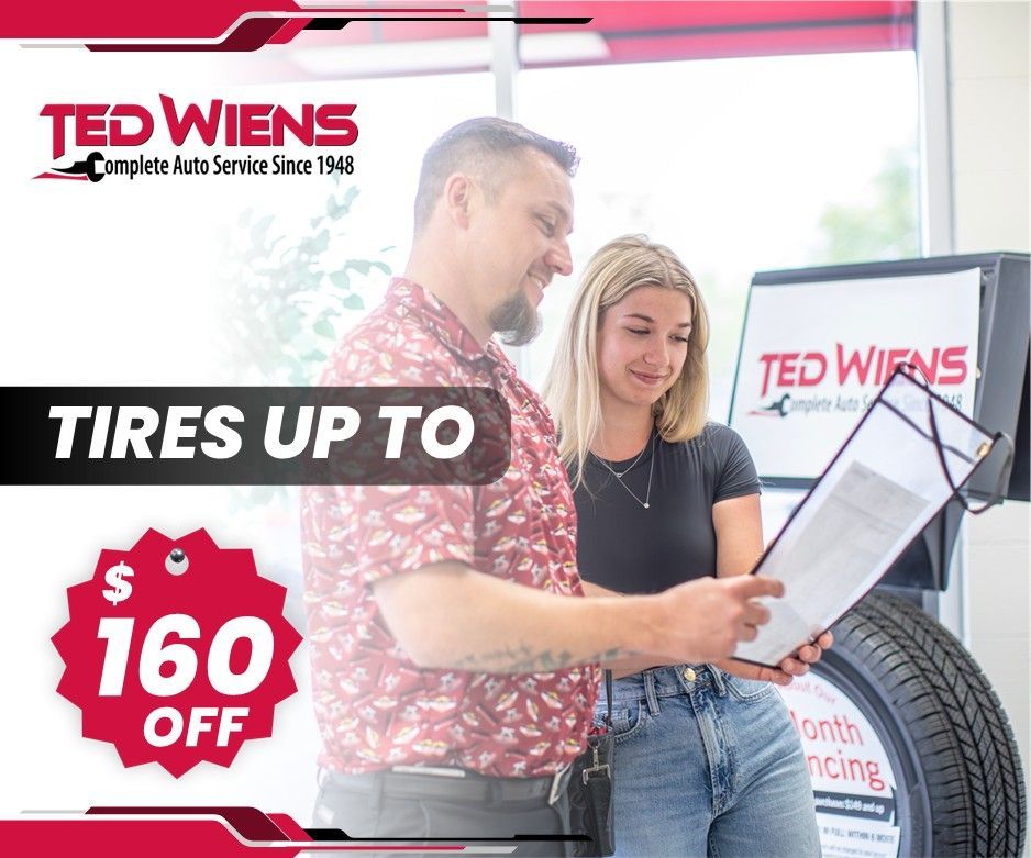 A man and a woman are looking at tires in a store.
