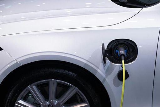 A white car is being charged with a yellow cord