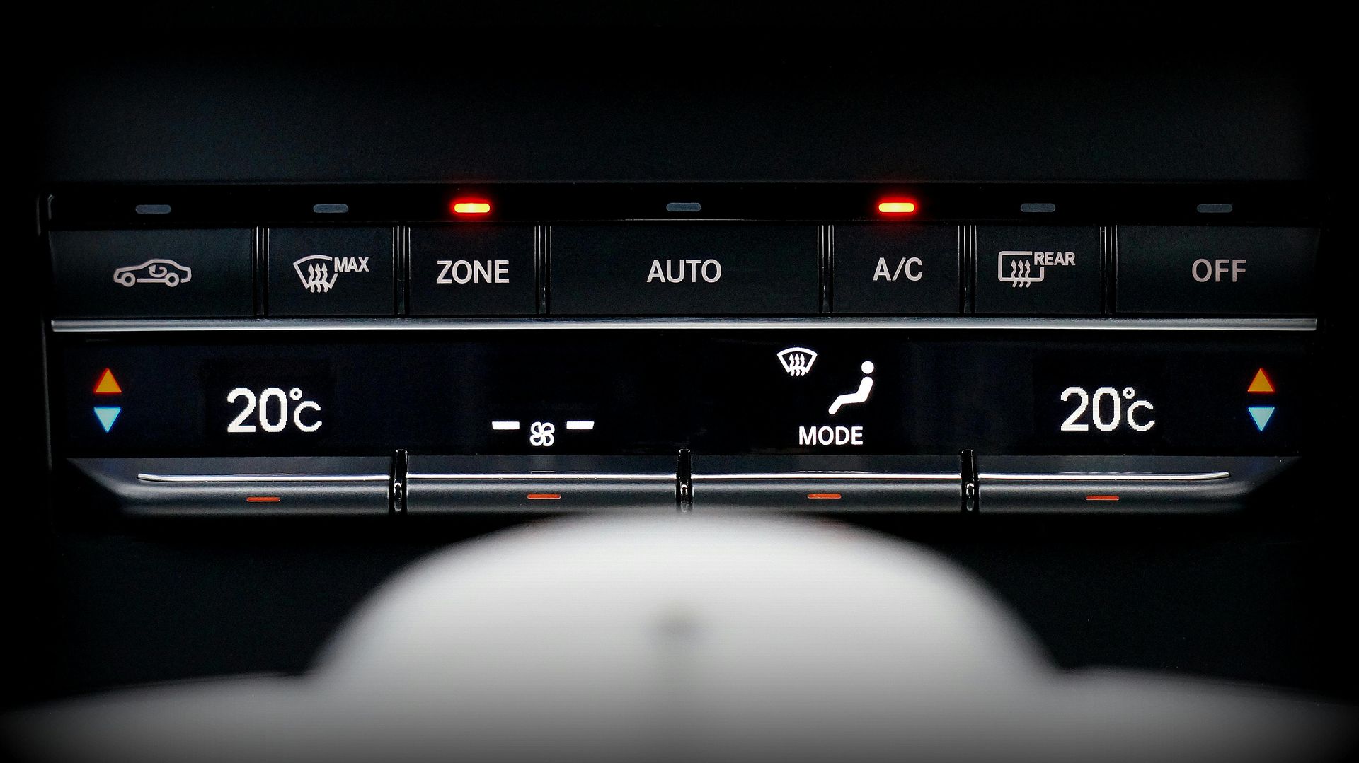 Car's climate control panel with illuminated buttons and digital temperature displays set to 20°C.