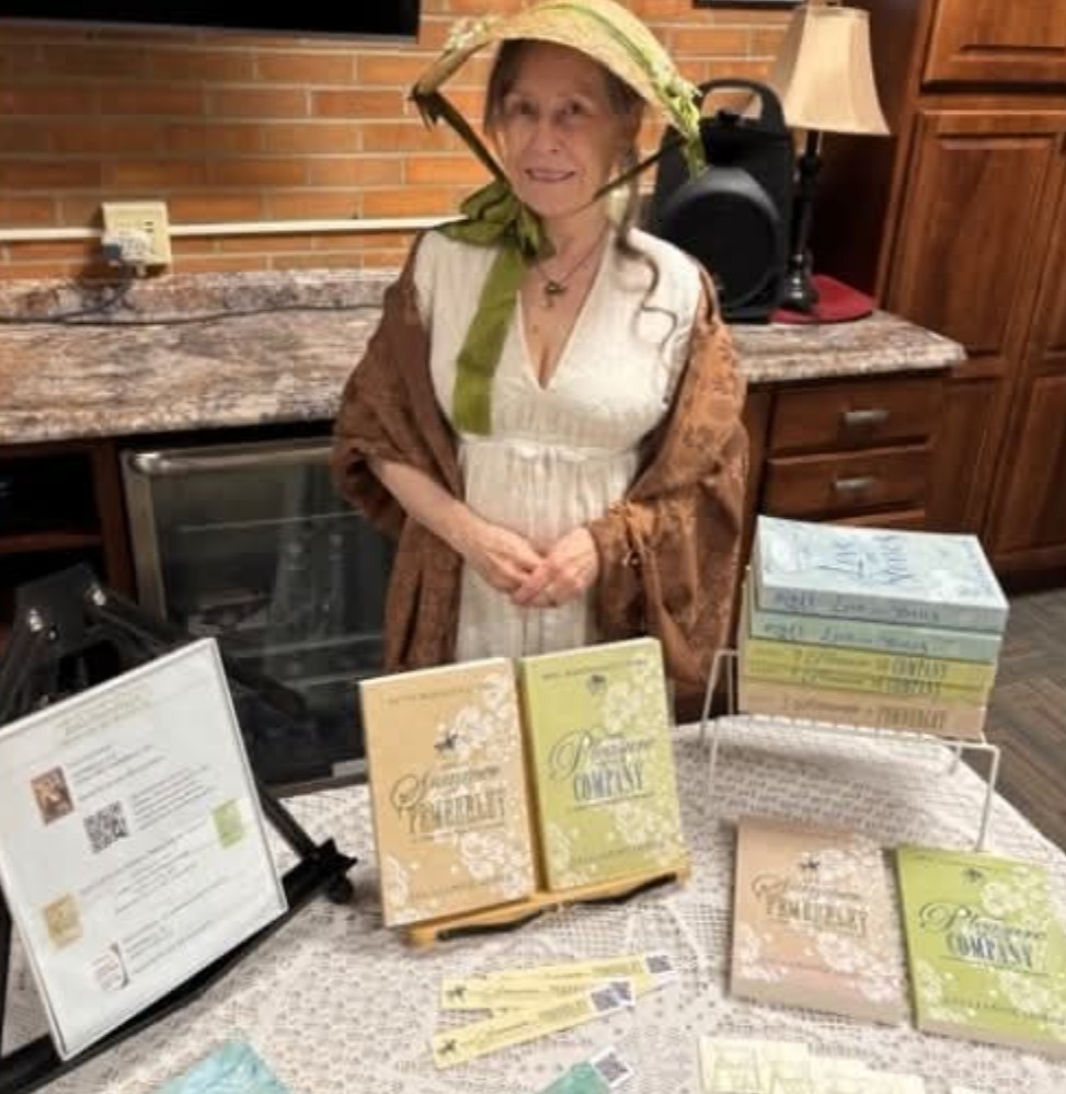 Woman in period attire stands at a table with books, wearing a bonnet. Indoor setting.