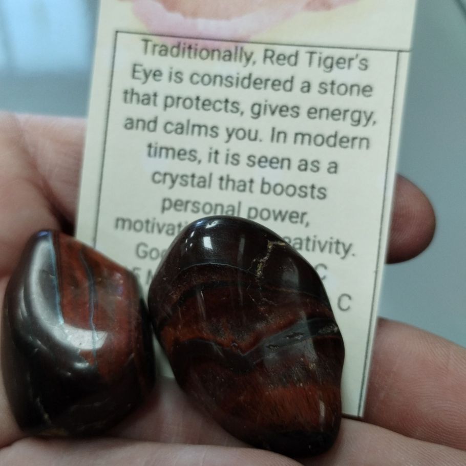 Two polished red tiger's eye stones held with a description card.