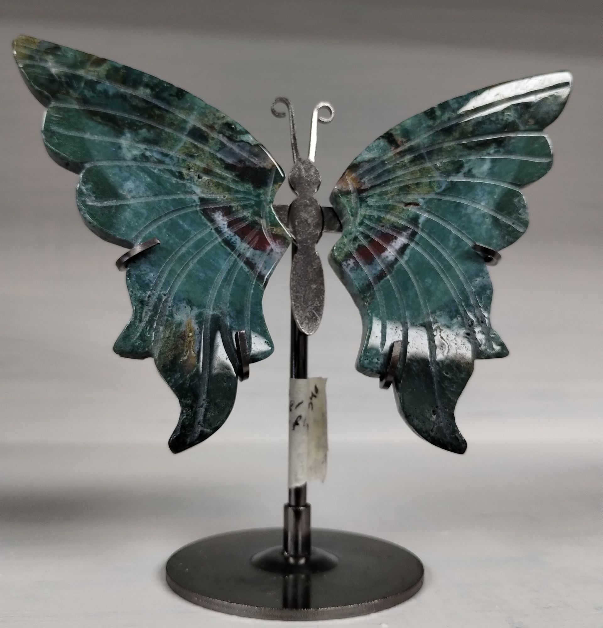 A butterfly sculpture made of green and white patterned stone, mounted on a metal stand.