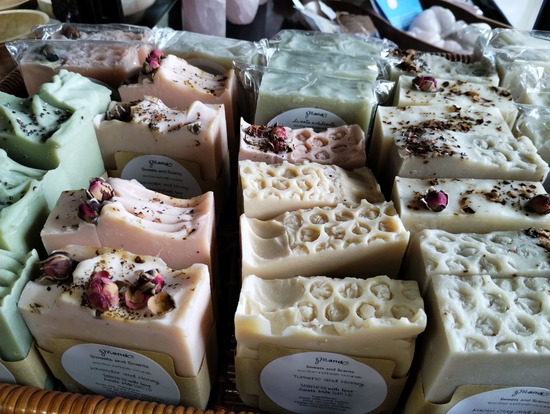 Assortment of handmade soaps in various colors and designs, some with dried flowers or textured patterns.