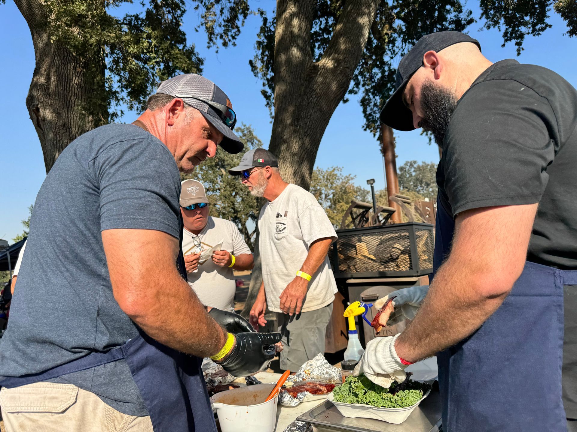 A group of men are standing around a table preparing food.