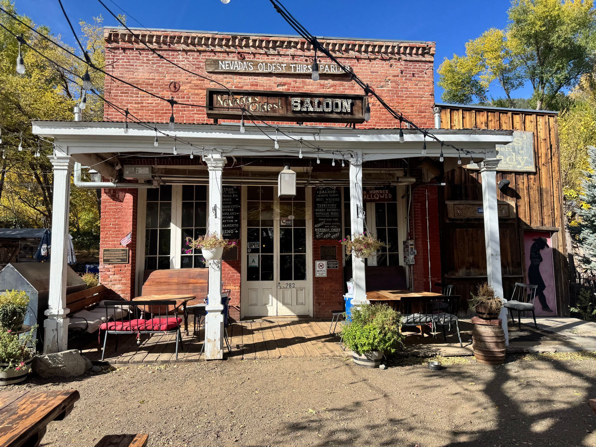 A brick building with a porch and tables in front of it.