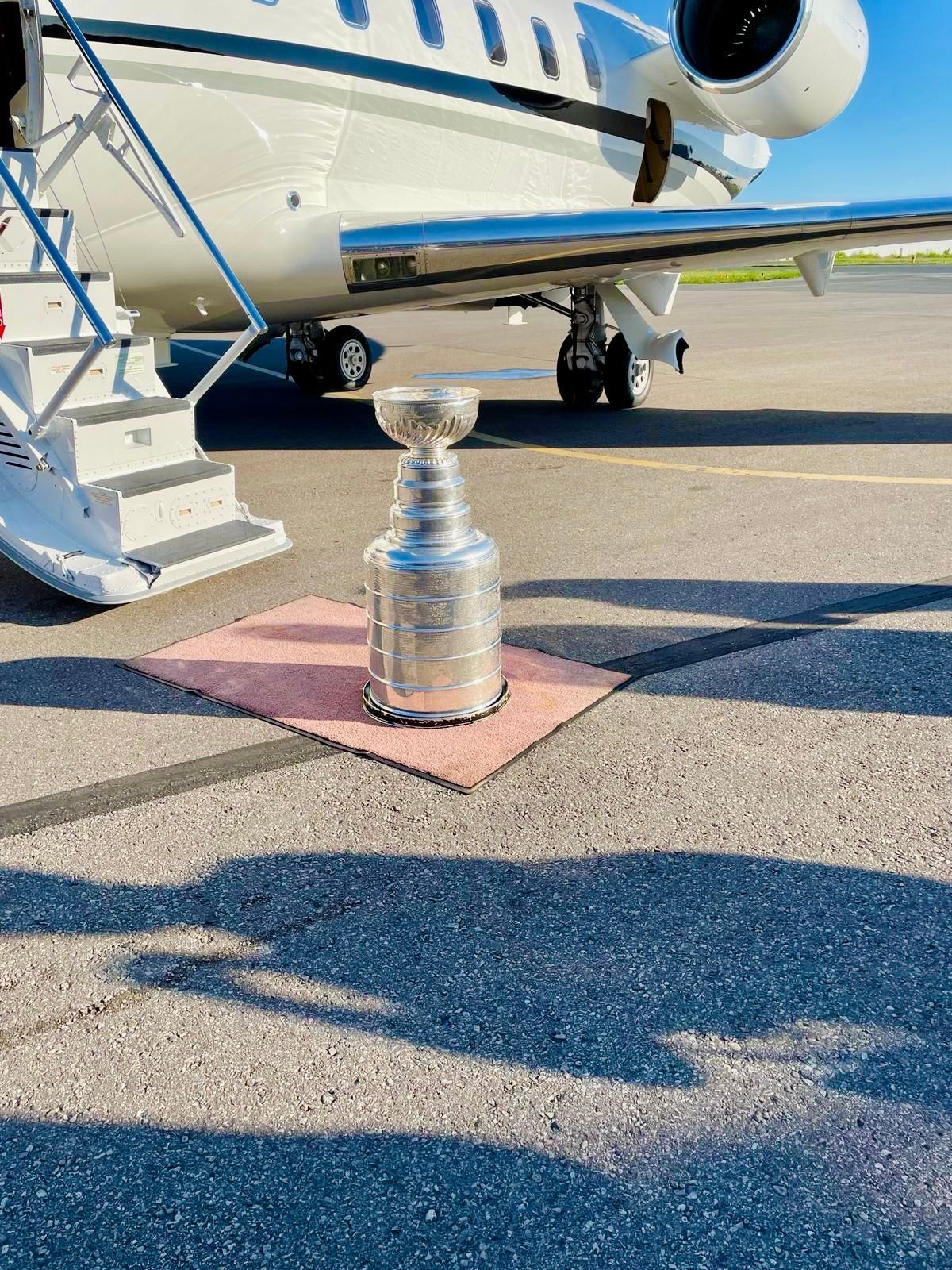 A trophy is sitting on the ground in front of a plane.