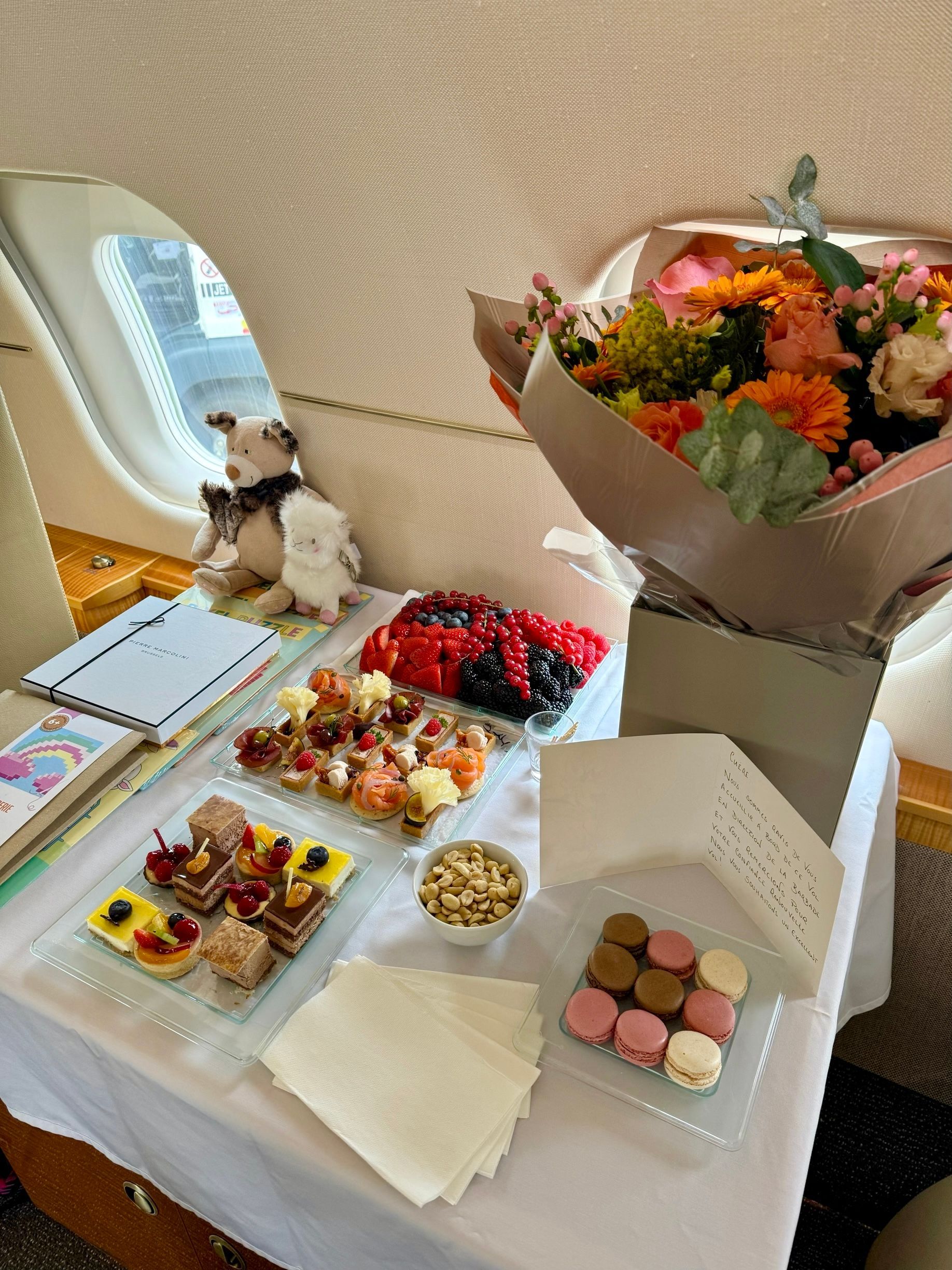A table with plates of food and flowers on it on a plane.