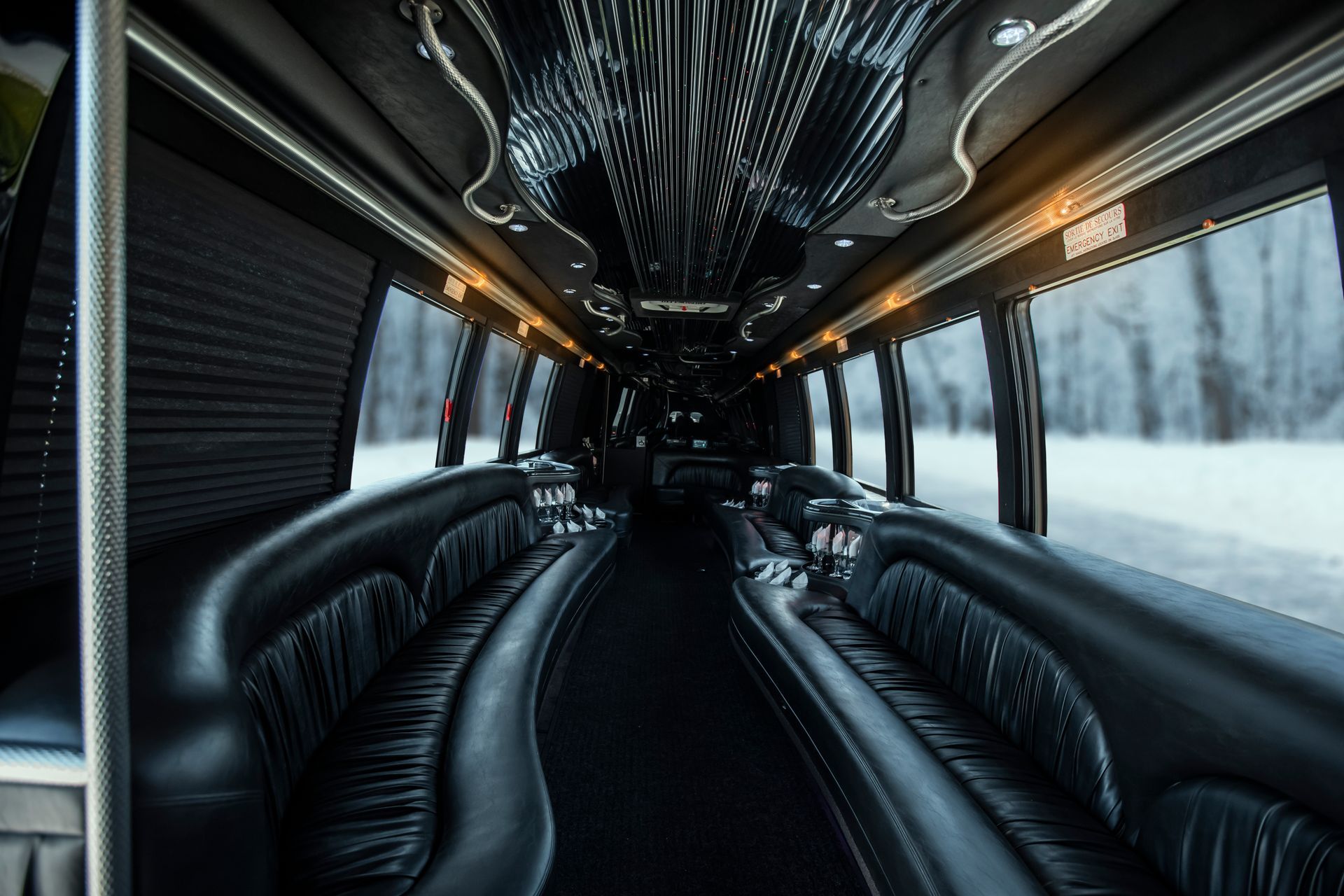 The inside of a limousine with lots of black leather seats.