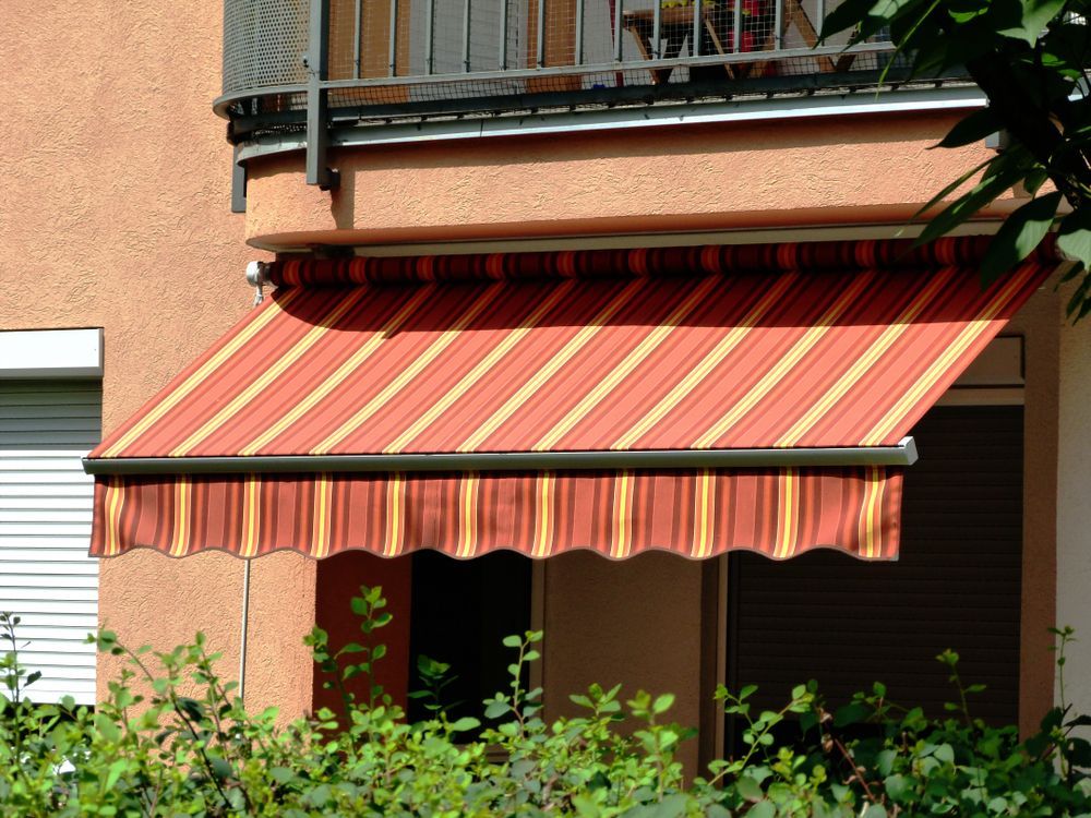 A Red and Yellow Striped Awning on a Balcony — Simply Smarter Blinds in Tea Gardens, NSW