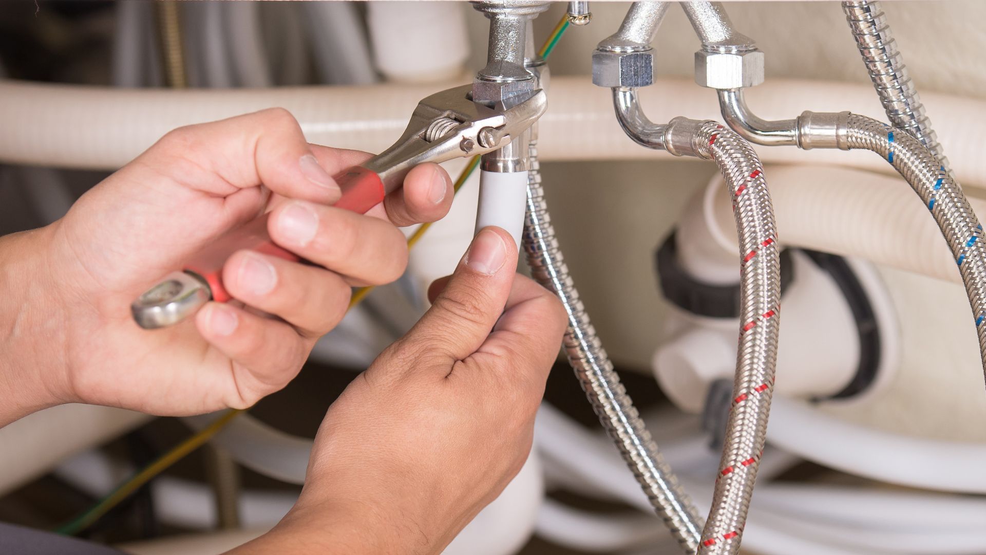 A plumber is fixing a sink with a wrench.