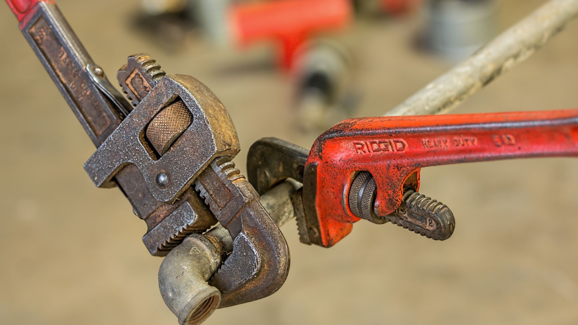 A close up of two wrenches on a pipe.