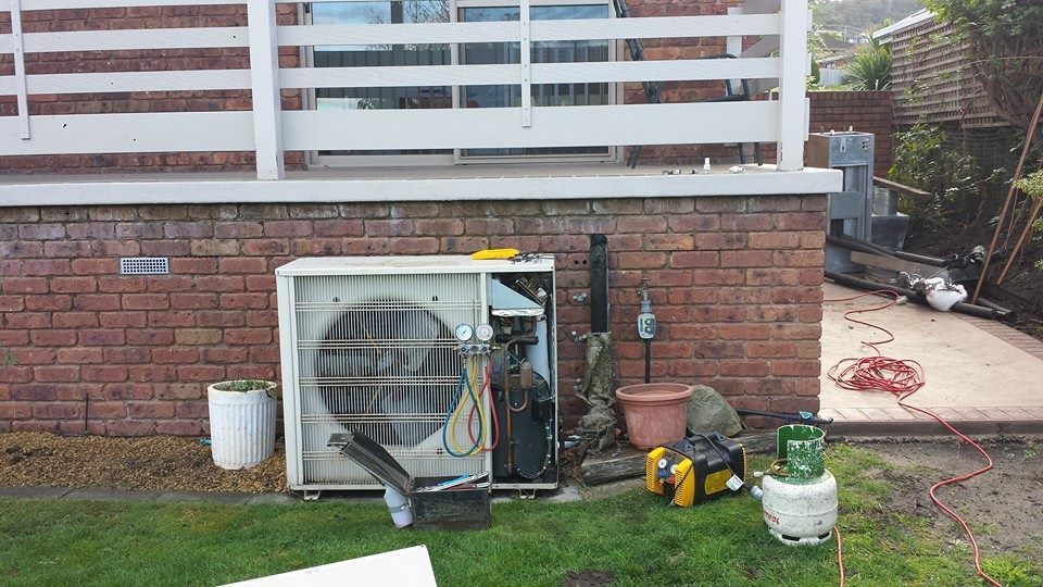 A Broken Air Conditioner Is Sitting Outside of A Brick Building- Hobart, TAS - The Heat Pump Man