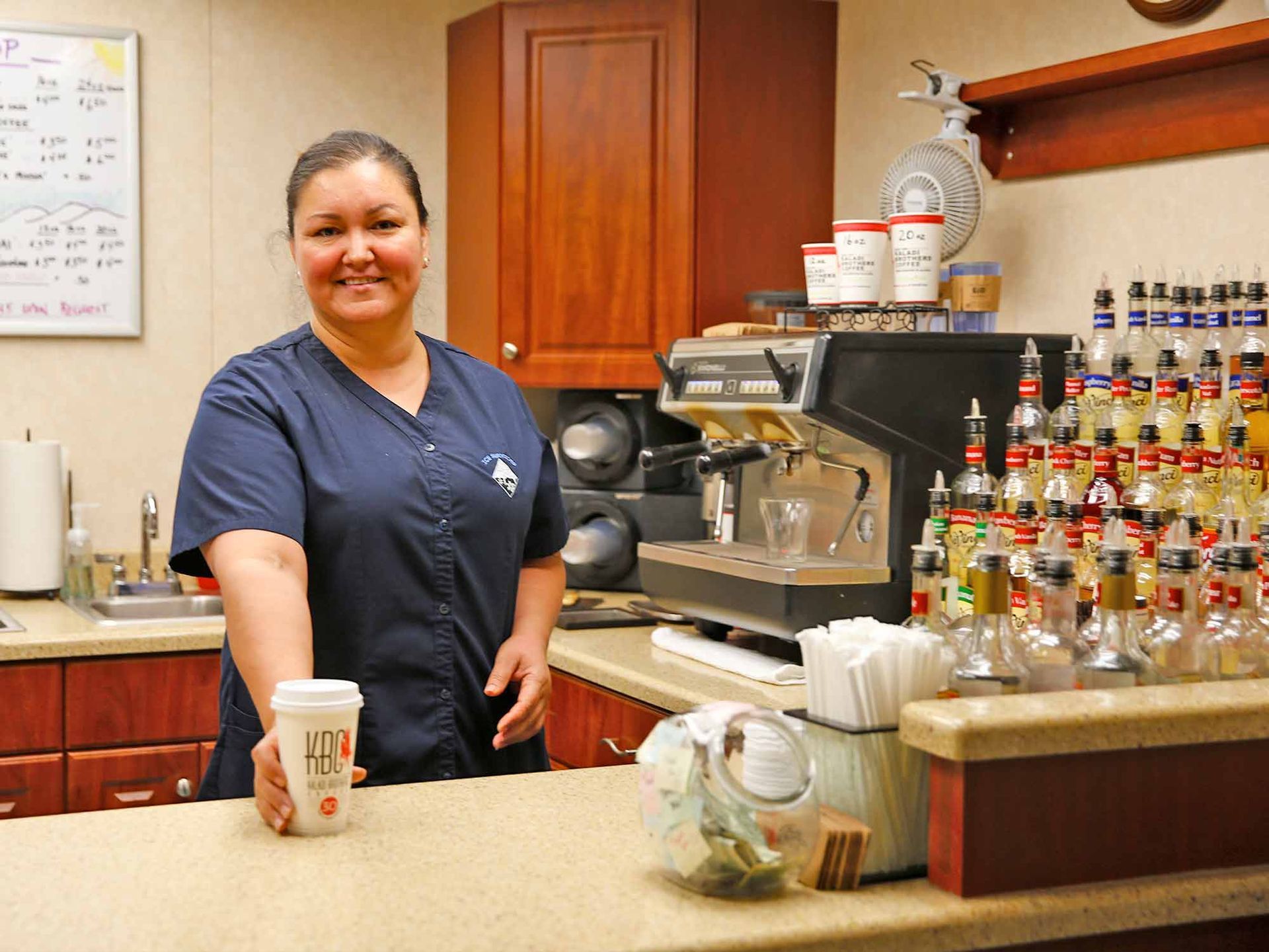A woman standing behind a counter holding a cup of coffee