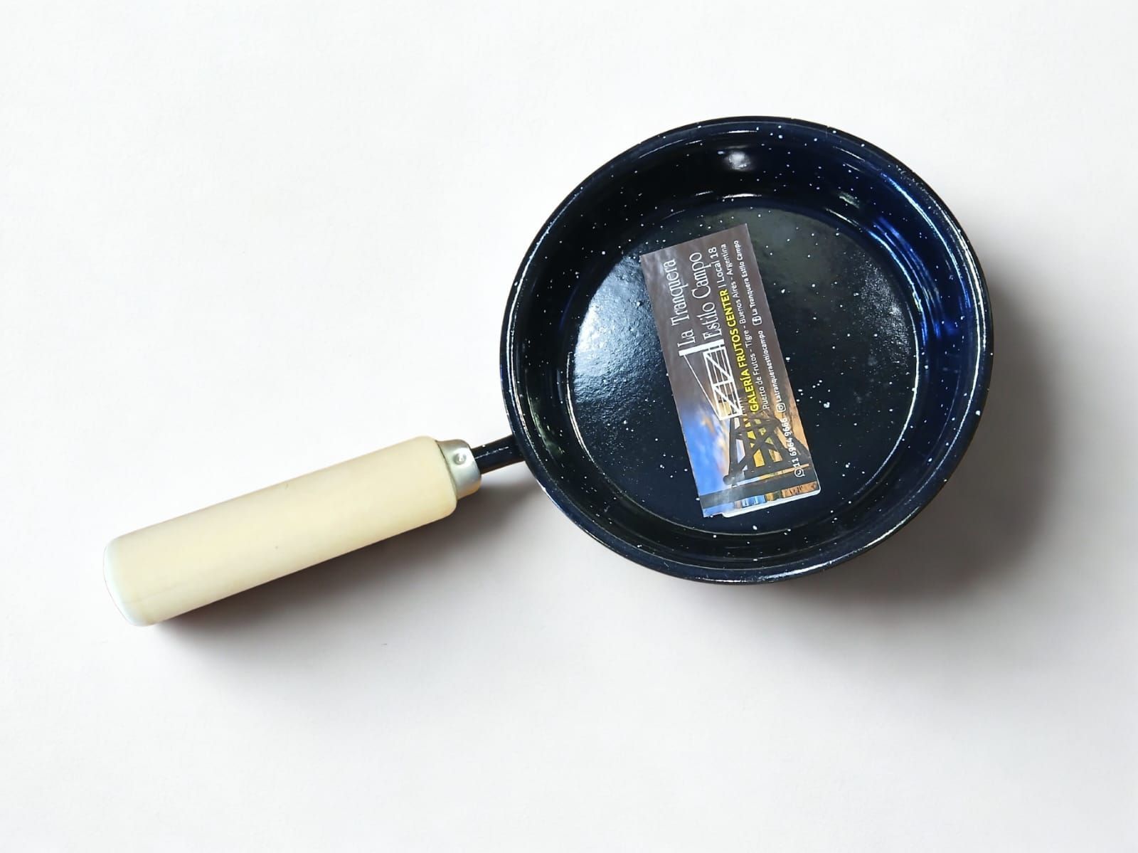 Sartén de esmalte azul con mango de madera sobre superficie blanca.