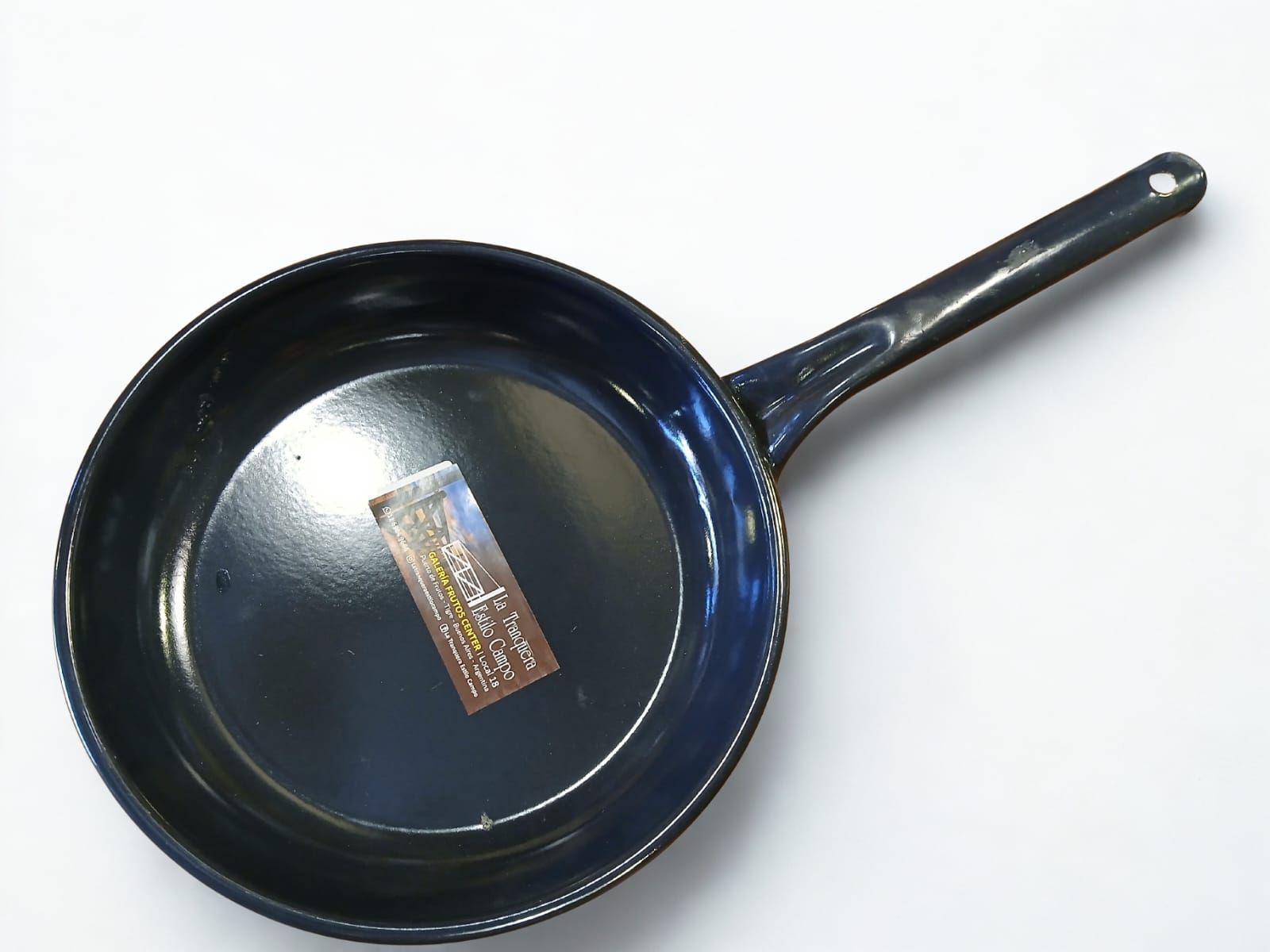 Sartén negra sobre superficie blanca con interior brillante.