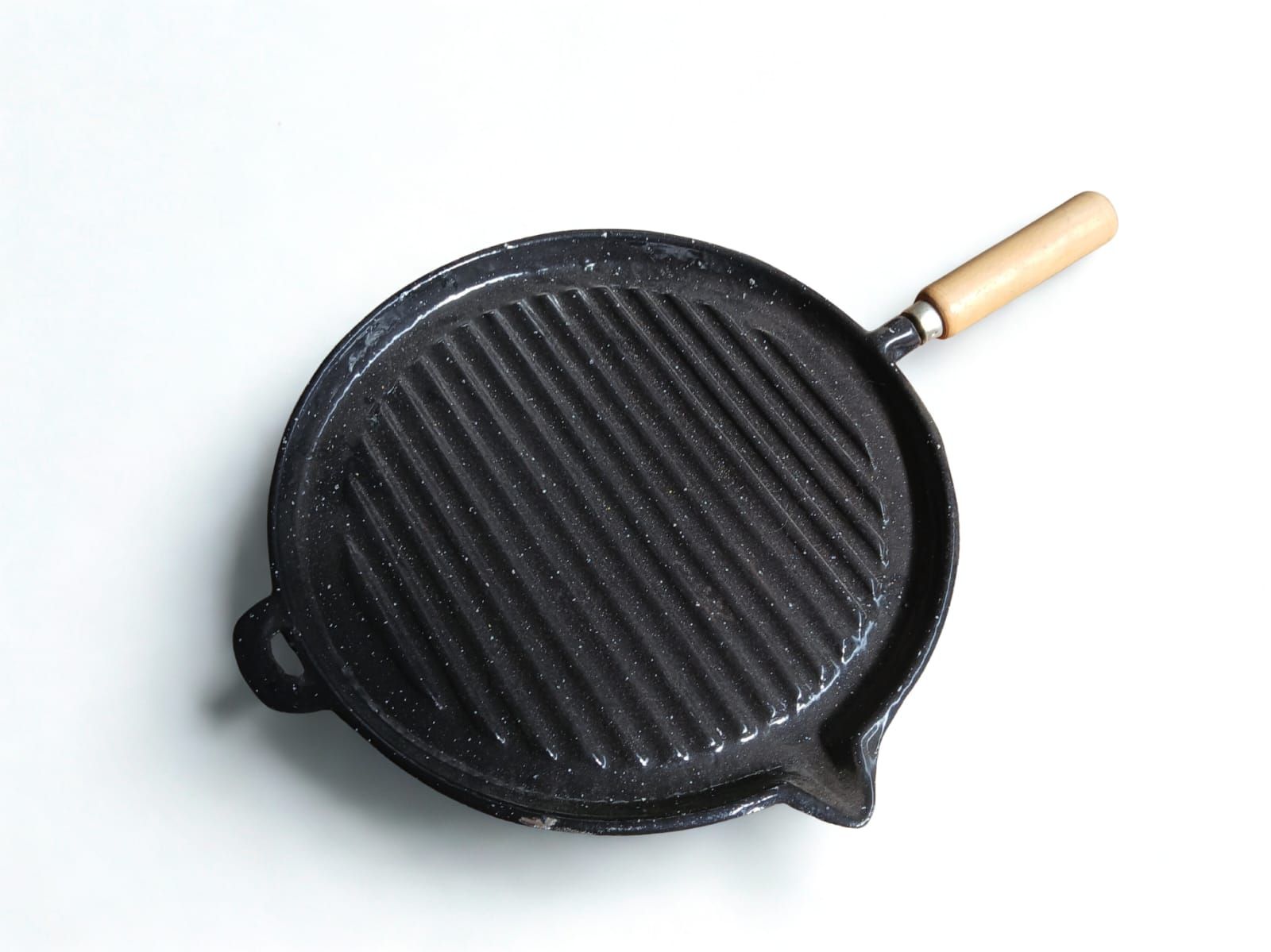 Parrilla de hierro fundido negro con mango de madera sobre superficie blanca.