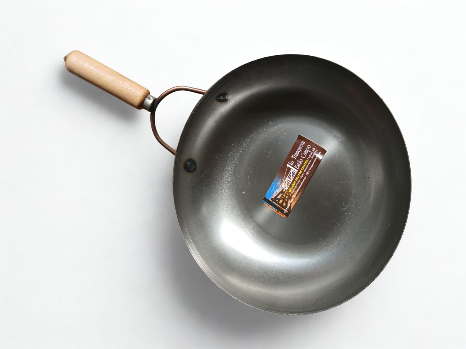 Sartén wok con mango de madera y caja en su interior sobre superficie blanca.