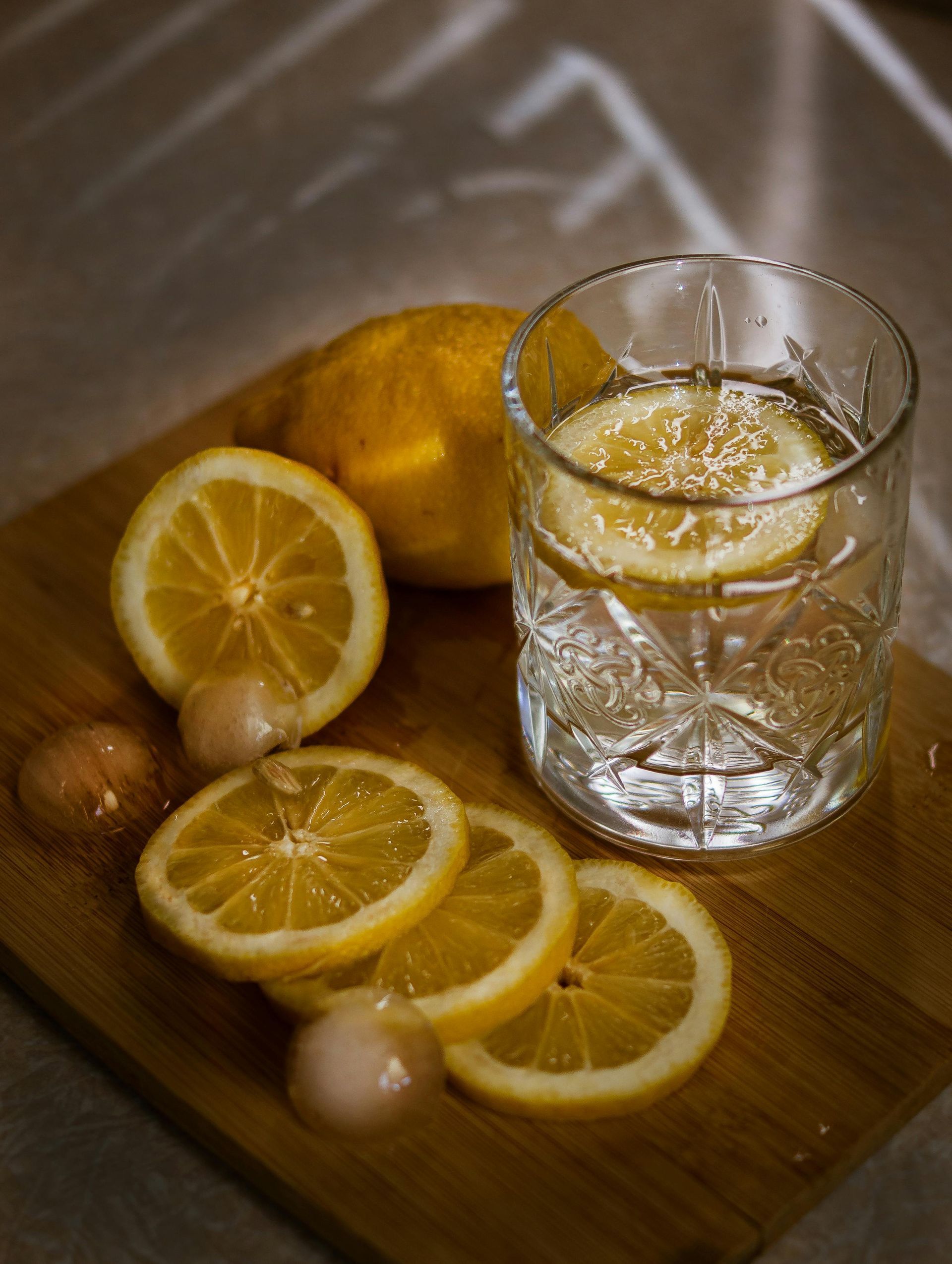 chopped lemon on a cutting board with a glass of lemon water