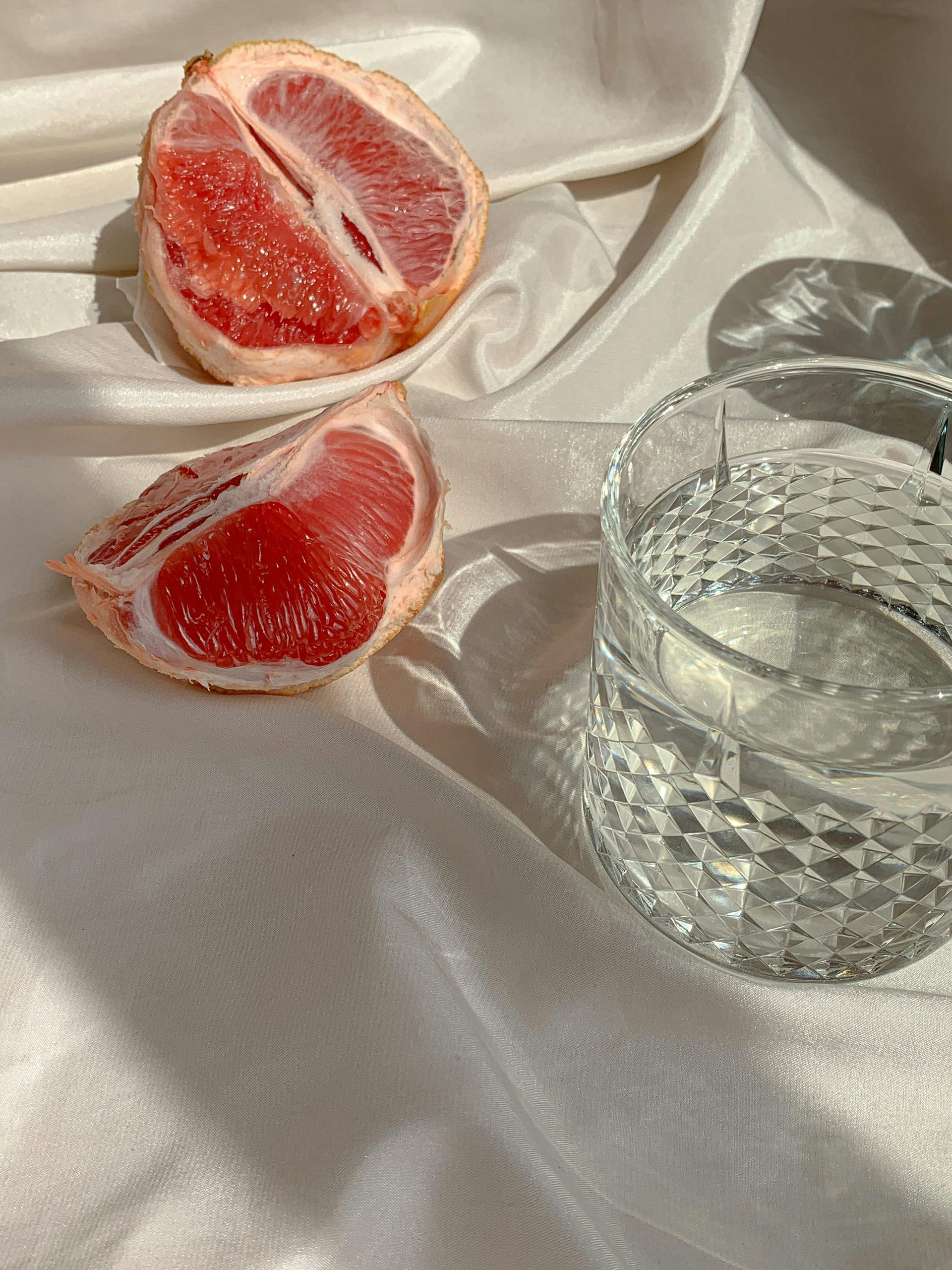 blood orange on white sheet with glass of water