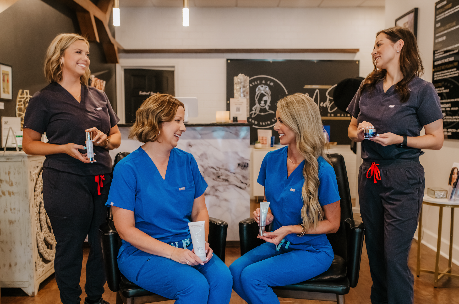 The staff at medispa on main posing with ZO skin care products. they are wearing black and blue scrubs