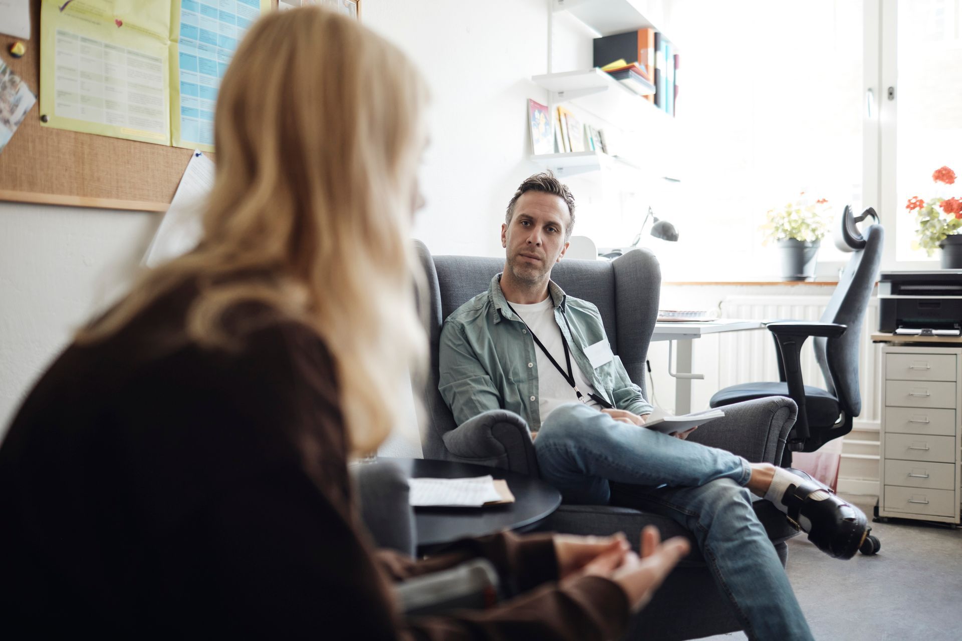 A man is sitting in a chair talking to a woman.
