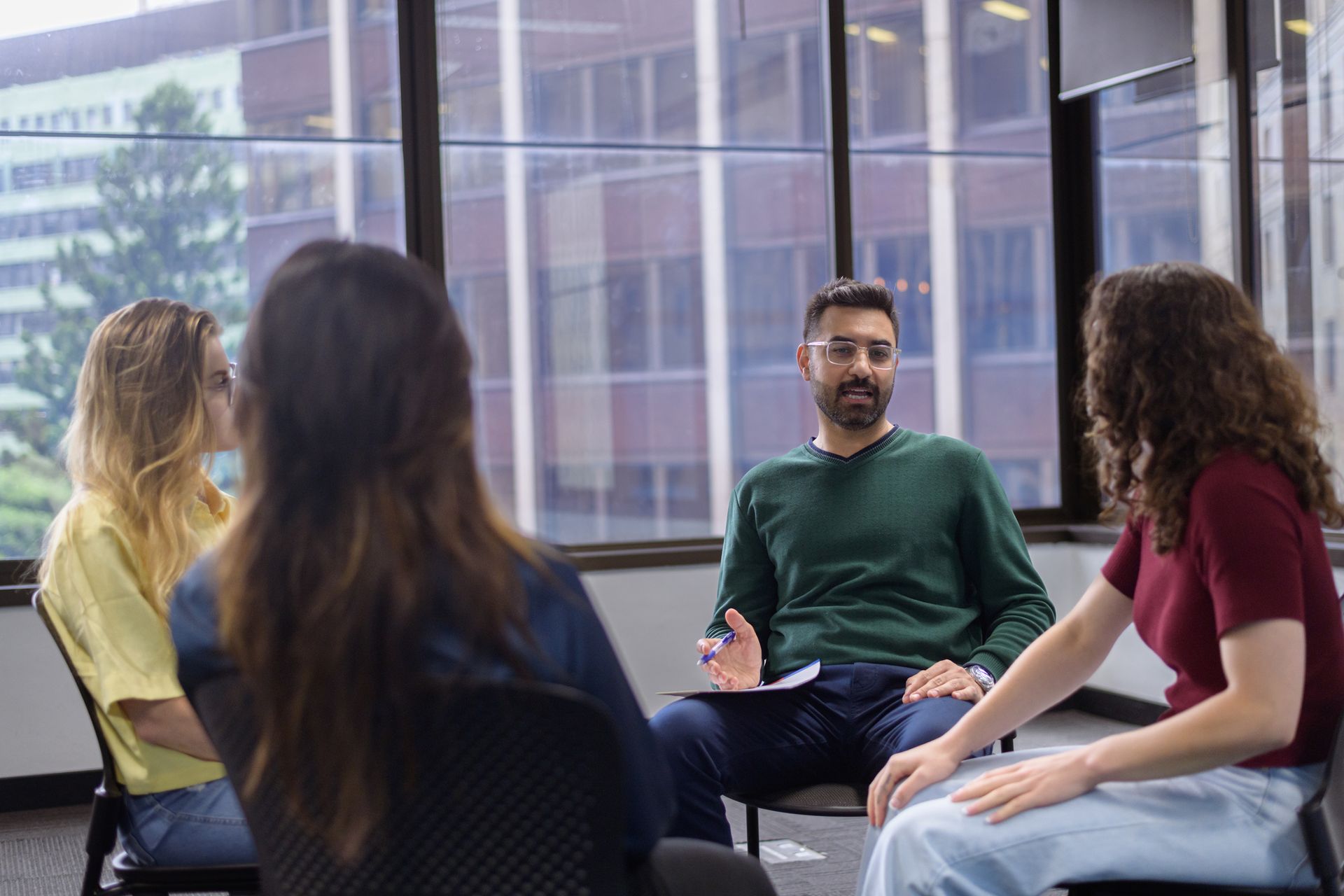 A group of people are sitting in a circle talking to each other.