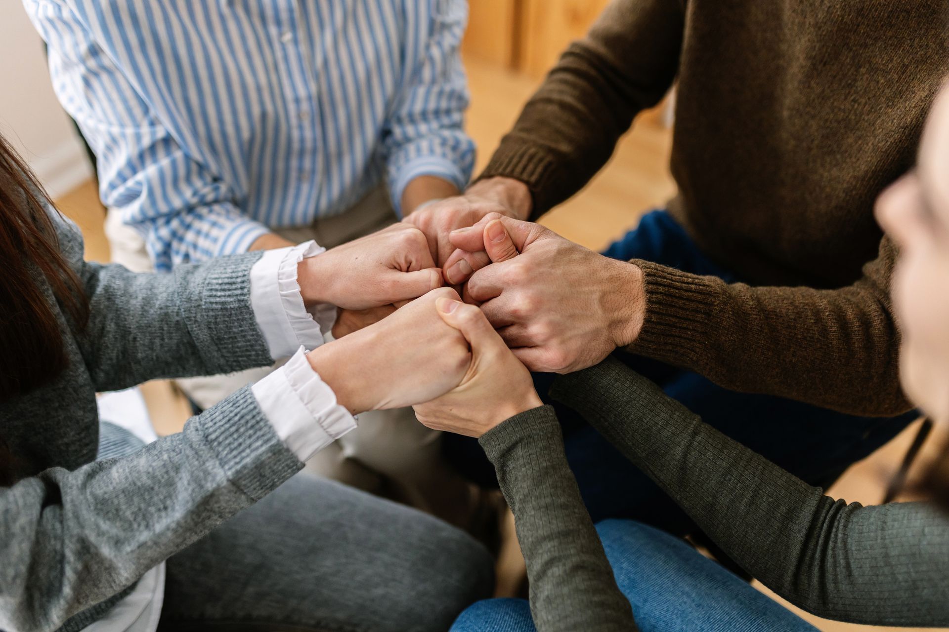 A group of people are sitting in a circle holding hands.
