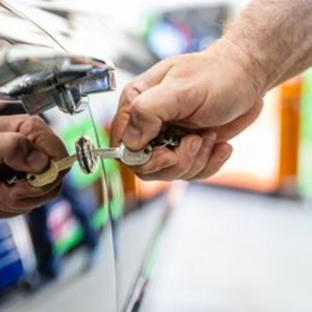 A person is opening a car door with a key.