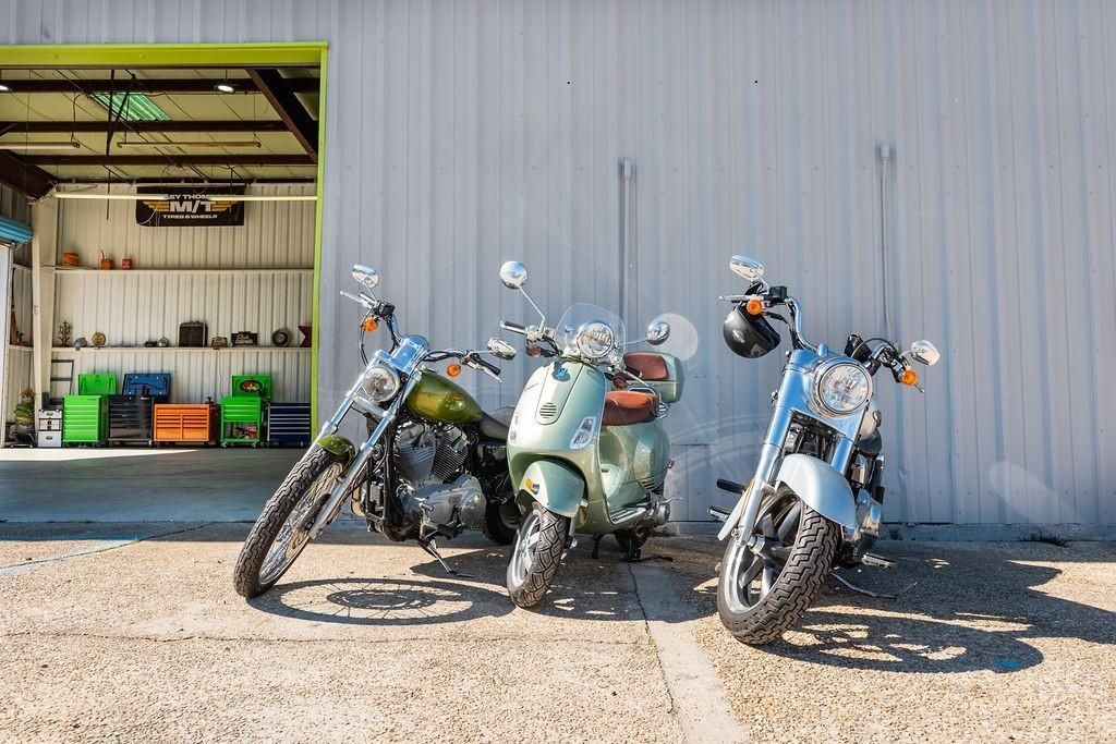 Three motorcycles are parked in front of a garage.