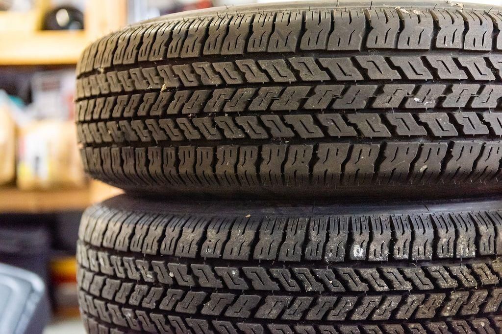 Two tires are stacked on top of each other in a garage.