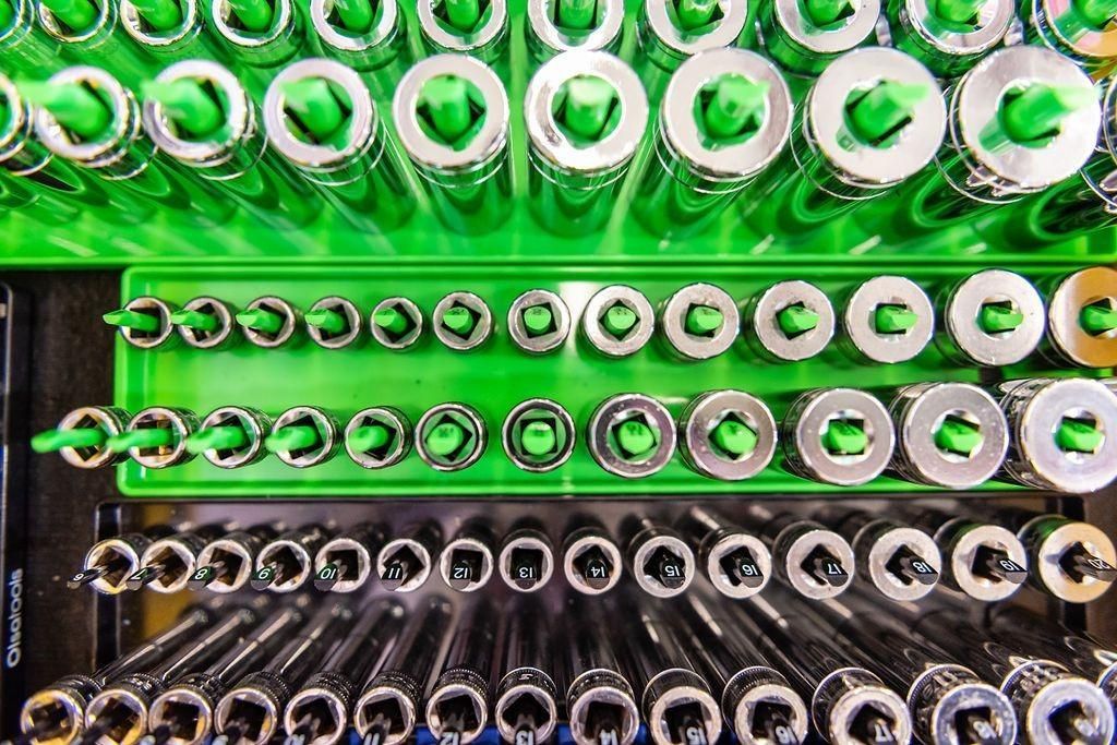 A bunch of nuts and washers are lined up on a green tray.