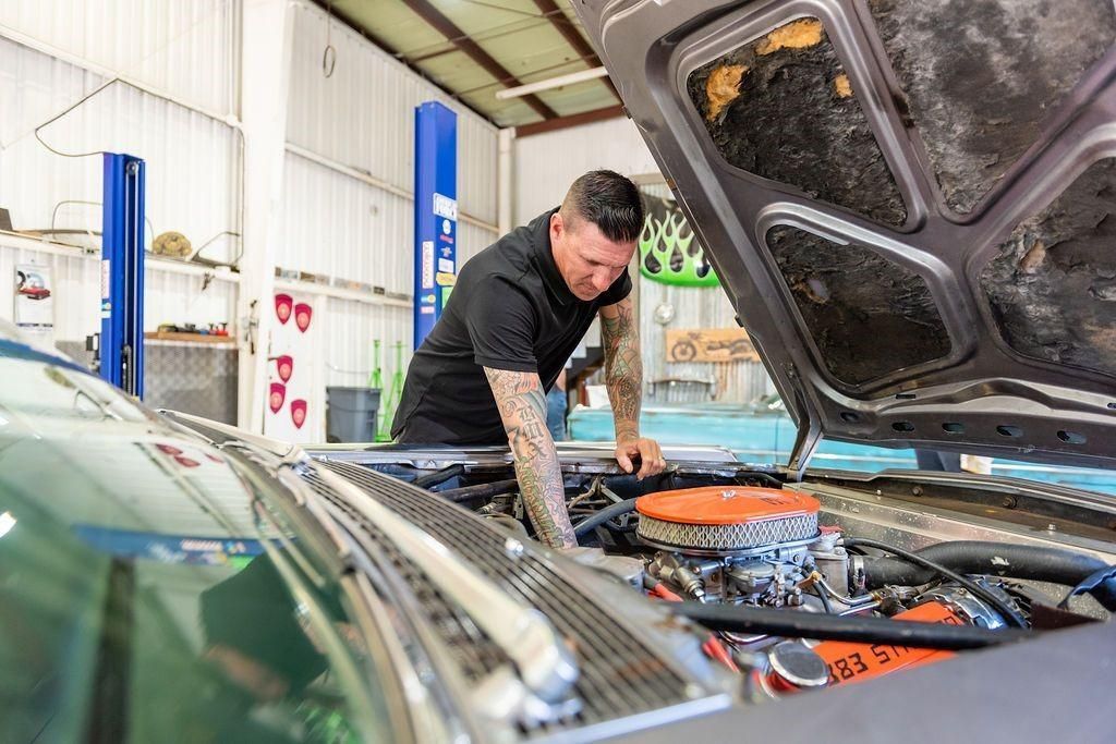 A man is working on the engine of a car in a garage.