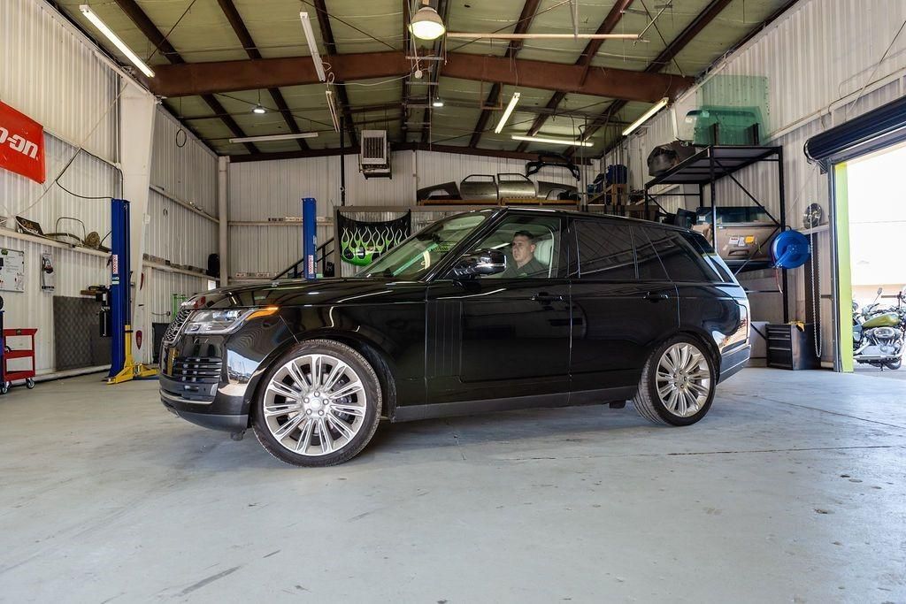 A black car is parked in a garage with a roof rack.