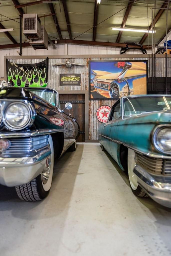 Two old cars are parked next to each other in a garage.