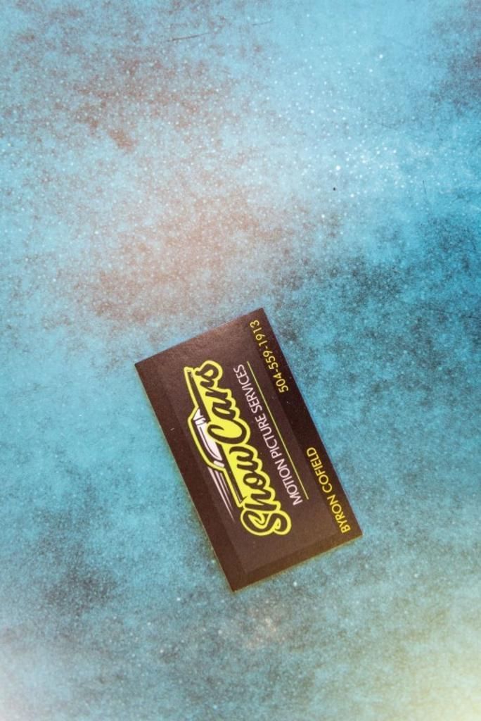 A business card for show cars is on a blue surface