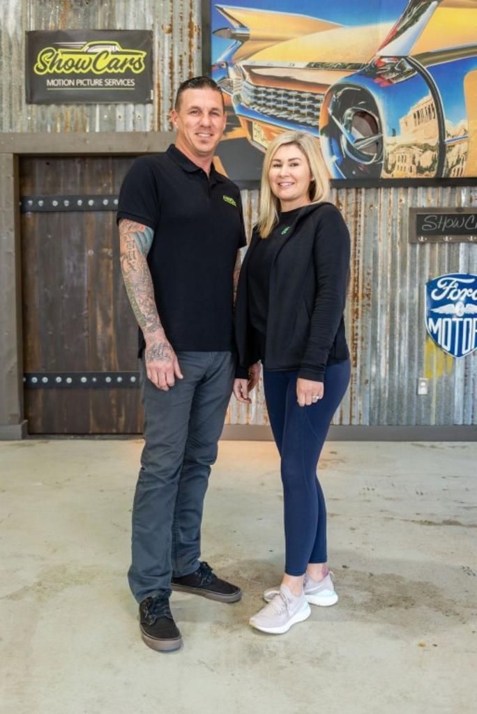 A man and a woman are standing next to each other in a garage.