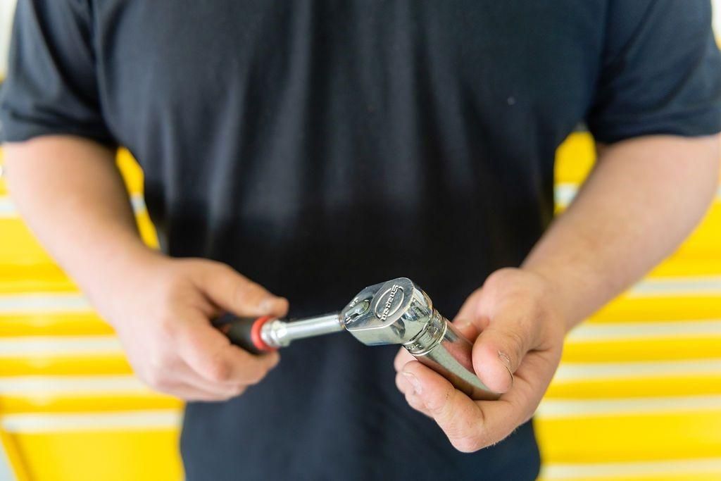 A man is holding a screwdriver and a wrench in his hands.