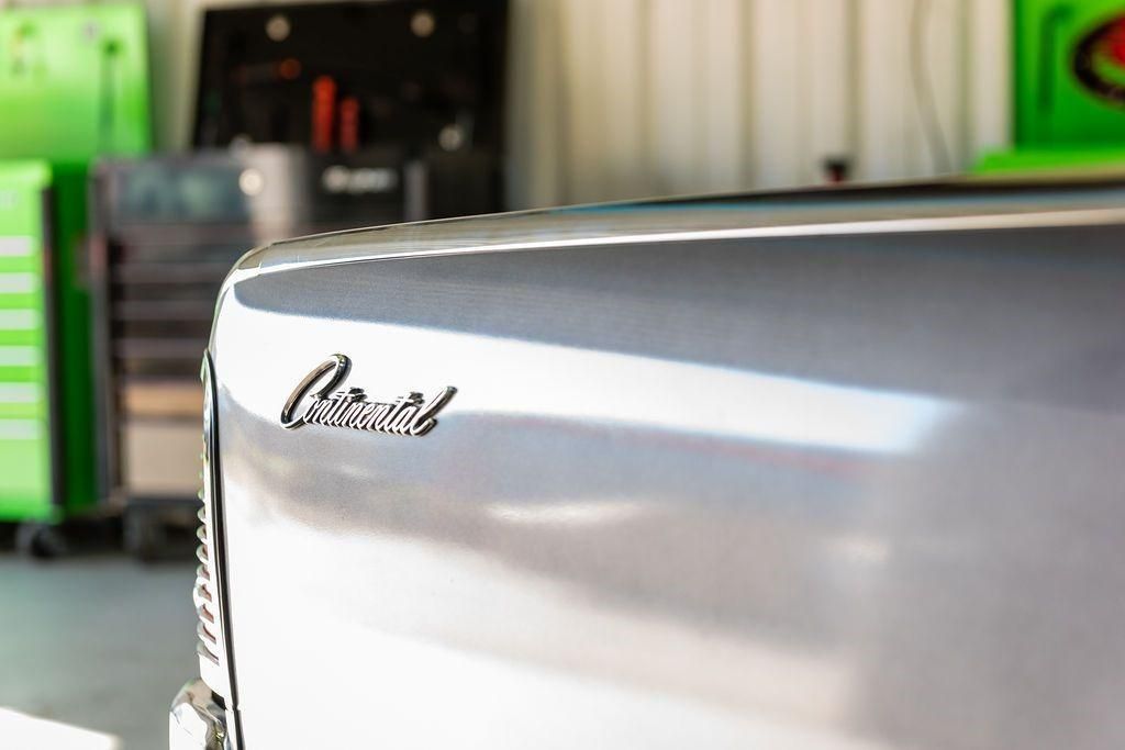 A close up of the back of a silver car in a garage.