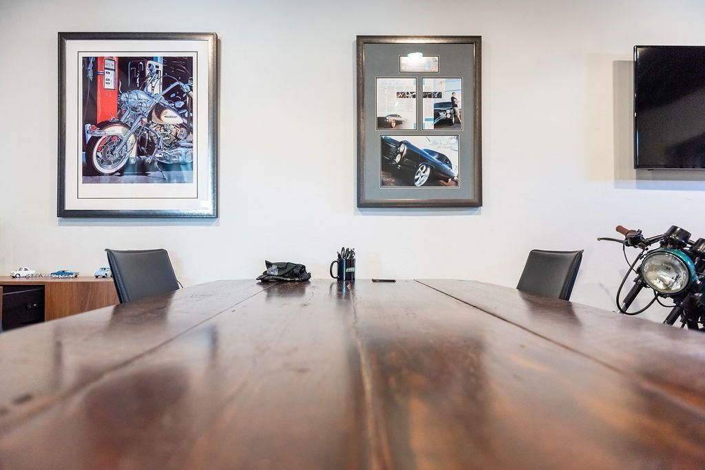 A conference room with a wooden table , chairs , and a motorcycle.