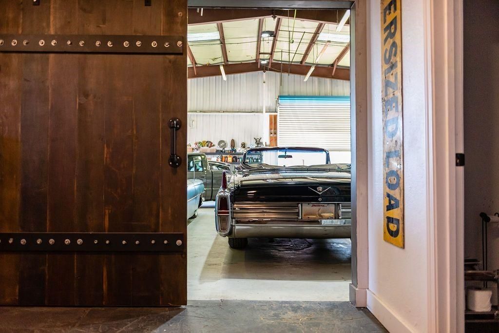 A car is parked in a garage next to a wooden door.