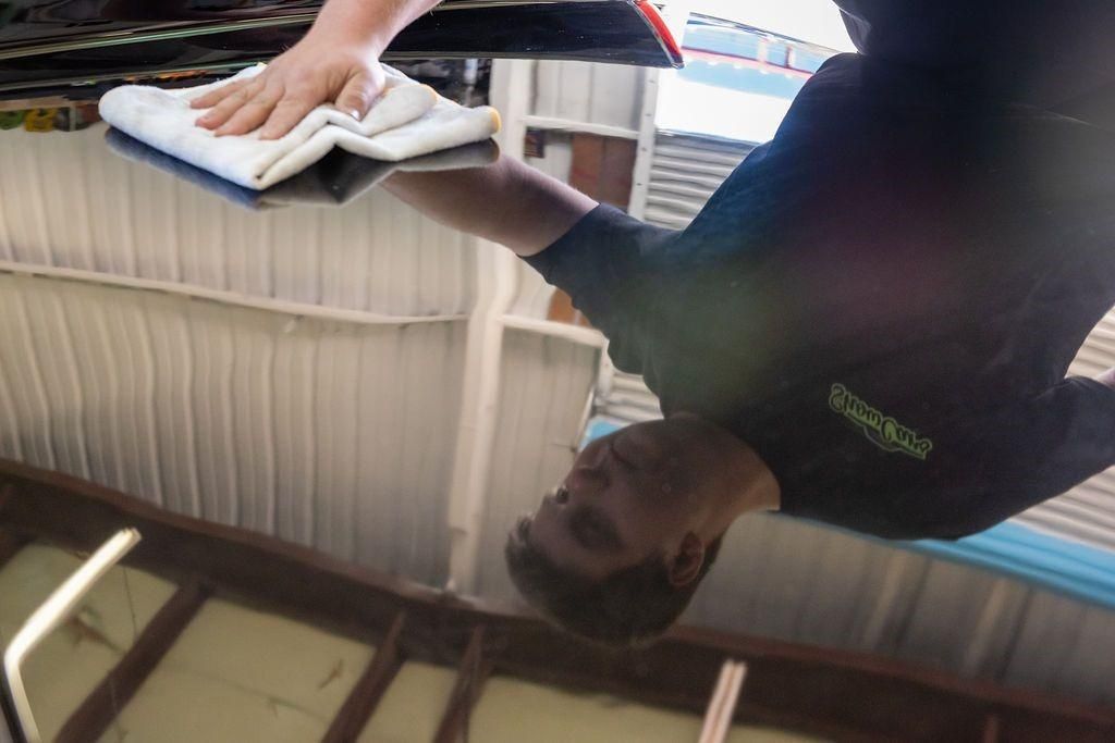 A man is cleaning a car with a towel.