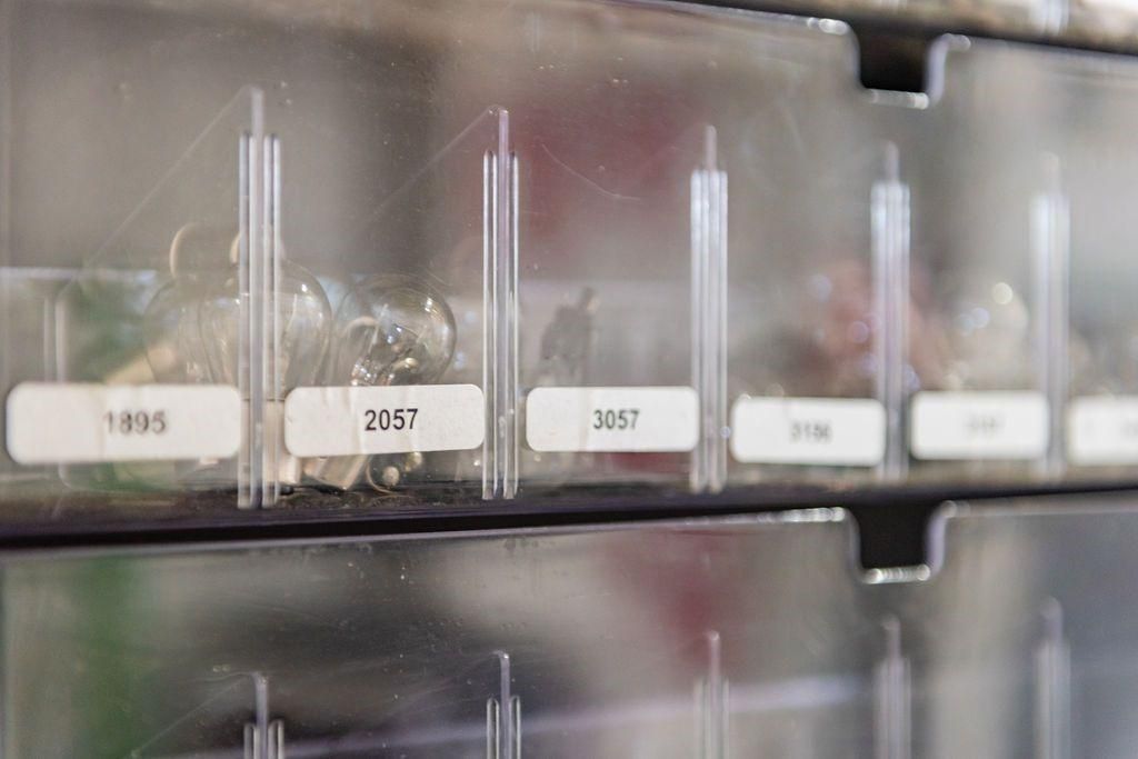 A row of clear plastic drawers filled with various types of screws.