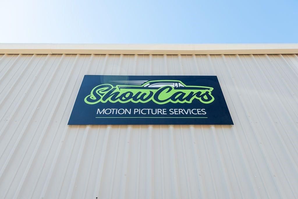 A sign on the side of a building says show cars motion picture services