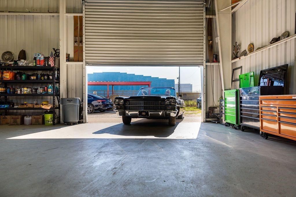 A truck is parked in a garage with the garage door open.