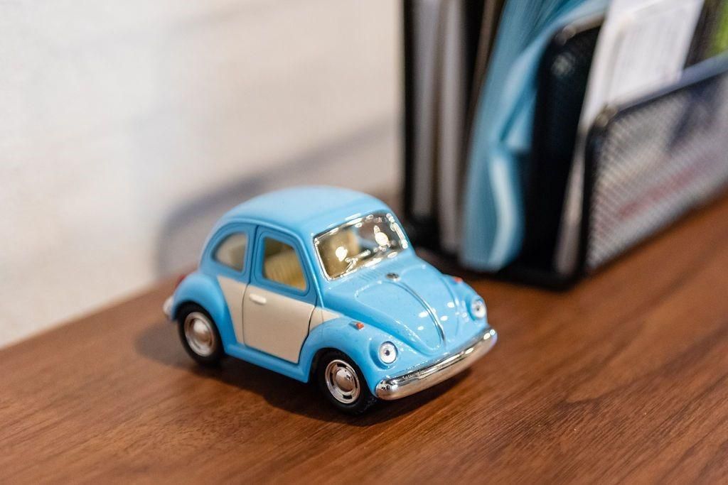 A blue toy car is sitting on a wooden table.
