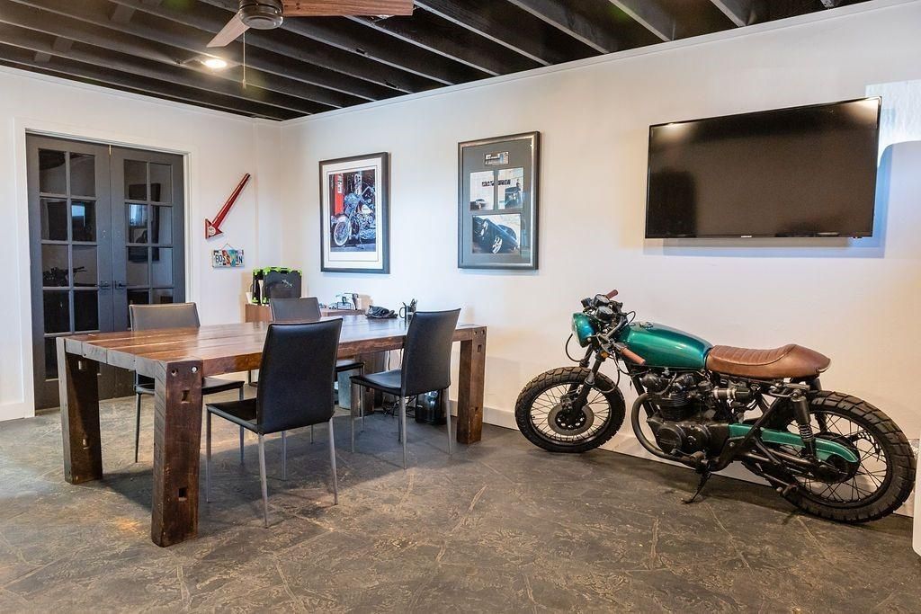 A motorcycle is parked in a room next to a table and chairs.